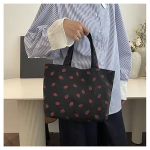 Détail d'un sac cabas en velours côtelé noir avec motif fraise et texture de l'anse