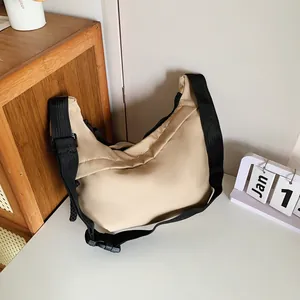 Detail of beige crescent crossbody bag with adjustable black strap and buckle
