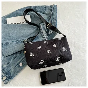 Detail view of black floral shoulder bag with embossed rose texture and metal hardware