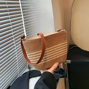 Close-up of a striped woven straw tote bag with brown leather straps and dense texture