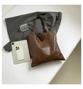 Macro detail of dark brown tote bag with geometric embossed pattern and glossy finish