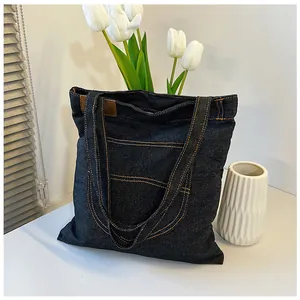 Detail of dark denim tote bag with yellow contrast stitching and leather trim