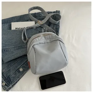 Borsa a tracolla azzurra con cerniera argentata e cinturino in nylon su tessuto bianco