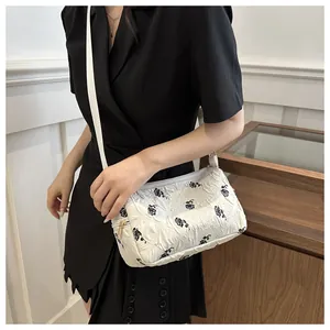 Detailed shot of white shoulder bag with floral print and crinkled texture on model
