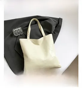 Detail shot of cream tote bag featuring irregular geometric stitching and soft leather