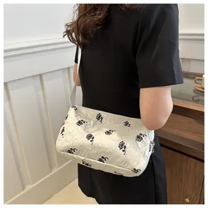 Detail of white quilted tote bag with black rose floral print on model in black dress