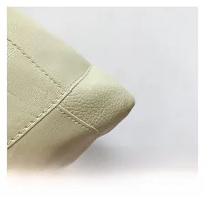 Detailed close-up of cream leather texture with high-quality parallel stitching on tote bag