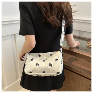 Detail view of white floral jacquard shoulder bag with black rose print on female model