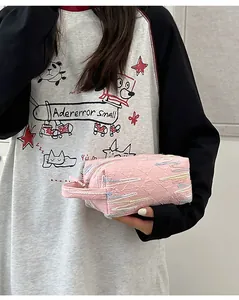Roze gewatteerde clutch met gekleurde golfstiksels en handige handgreep van band