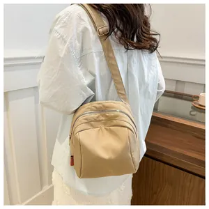 Dettaglio borsa a tracolla in nylon kaki con tre scomparti a zip e design plissettato