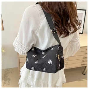 Detail of floral pillow bag showing black fabric with white rose print and gold hardware