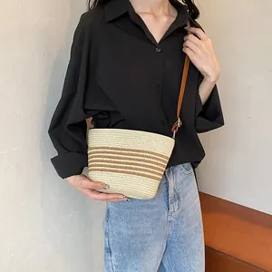 Minimalist woven straw crossbody bag with brown striped design and leather shoulder strap