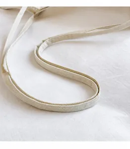 Close-up of the reinforced stitching and woven texture on a cream canvas shoulder strap