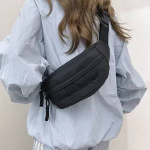 Detail of black nylon chest bag showing embossed letters and woven rope zipper pull