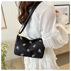 Detail of floral texture and adjustable strap on the black rose patterned shoulder bag