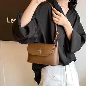 Details einer braunen Umhängetasche aus Leder mit goldener Schleifenschnalle und Matt-Finish