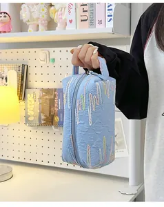 Detail van lichtblauwe gewatteerde handtas met kleurrijk borduursel en ritssluiting