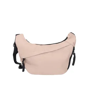 Minimalist beige half-moon crossbody bag with adjustable black nylon strap and zipper