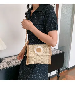 Close-up of woven straw crossbody bag with white sunflower detail worn by model