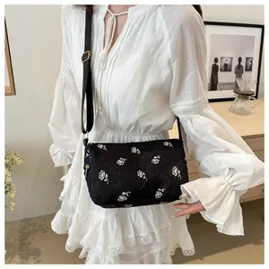 Detail of elegant black floral handbag with 3D white rose pattern and adjustable strap