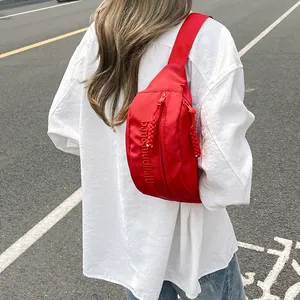 Close-up of red nylon crossbody bag featuring b.m&mudilafthed embroidery and double zippers