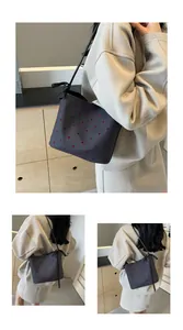 Detail van donkergrijze bucket bag met rode stippen en decoratieve strikken op de riemen
