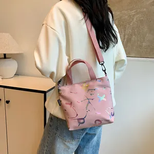 Detail of light pink crossbody bag with street style print and wide shoulder strap