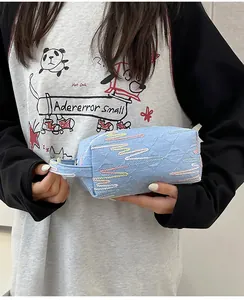 Detail van lichtblauwe geplooide handtas met kleurrijk zigzag borduursel en handvat
