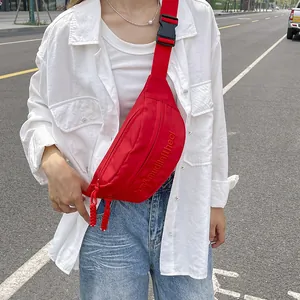 Detailed macro view of vibrant red canvas bag with white letter embroidery and strap buckle