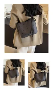 Detail van grijze bucket bag met sterpatroon, zwarte lintstrik en hoogwaardige stoftextuur