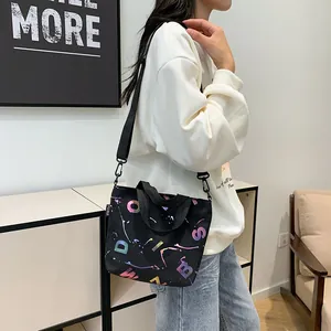 Detail of black canvas tote bag with colorful graffiti print and adjustable strap