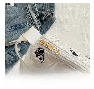 Detail of smooth gold zipper and white floral textured fabric on a shoulder bag