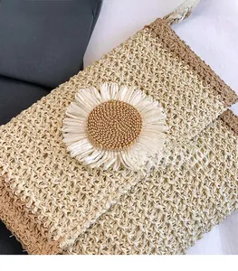 Detail of woven straw bag featuring a 3D white daisy ornament and natural texture