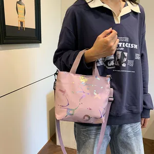 Detail of pink crossbody bag with colorful laser-printed letters and wide fabric strap