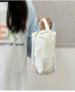 Detail van een witte clutch met textuur en kleurrijke abstracte geborduurde lijnen
