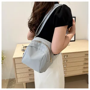 Mini borsa in nylon grigio-azzurro con zip dorate indossata da una modella in un interno
