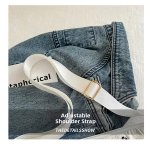 Detail view of denim crossbody bag with adjustable textile strap and gold hardware