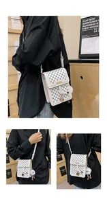 Detail of cream crossbody bag with grid texture, fashion lettering and plush ball charm