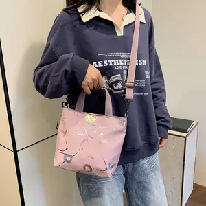 Detailed shot of pink crossbody bag featuring iridescent lettering and adjustable strap