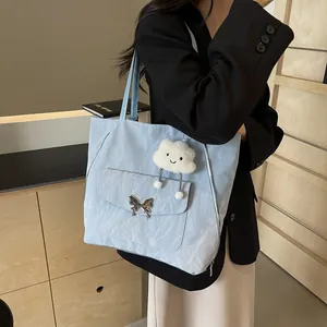 Close-up of light blue nylon tote bag with metal butterfly buckle and cloud charm detail