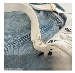 Detail of light gold metal ring buckle and wide white fabric strap on floral bag