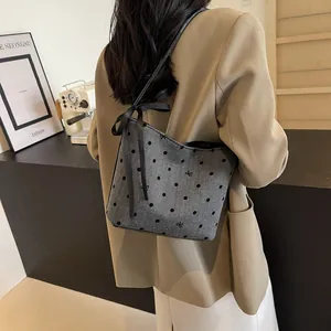 Detailweergave van grijze bucket bag met stippen, strikjes en stijlvolle V-vormige opening