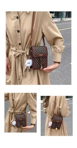 Detailed close-up of brown textured crossbody phone bag with gold metal plate and monster charm