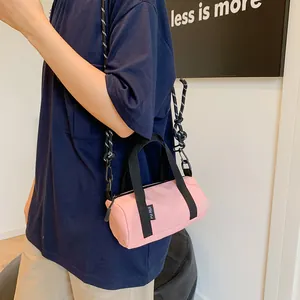 Detail of pink cylindrical mini crossbody bag with rope strap and brand label