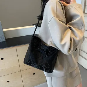 Détail d'un sac à épaule plissé noir avec un nœud délicat et une bandoulière fine