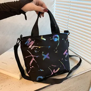 Detail of black canvas handbag with colorful gradient letters and woven shoulder strap