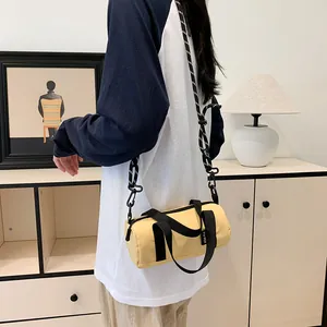 Detail of yellow nylon barrel bag with adjustable strap and contrast black webbing