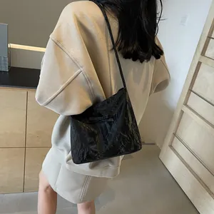 Détail du sac à bandoulière plissé noir avec un nœud décoratif et texture plissée