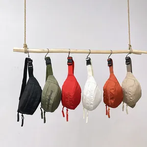 Minimalist nylon crossbody chest bags in six colors hanging on a wooden beam