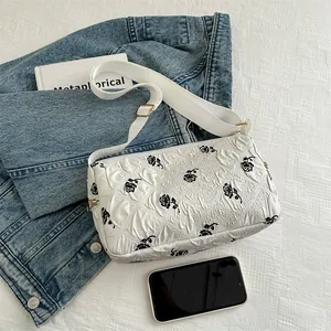 White floral tote bag with black roses and quilted texture on blue denim background